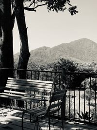 Empty bench by railing against mountains and clear sky