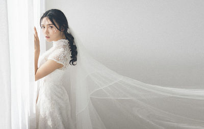 Side view of woman standing against white wall