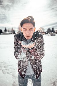 Playful man blowing powder snow during winter