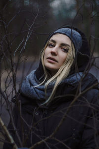 Portrait of woman amidst bare tree in winter