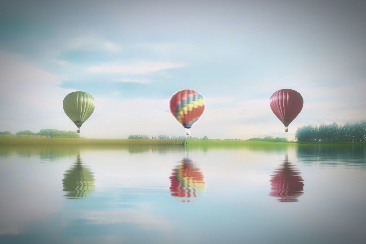 reflection, sky, tranquility, tranquil scene, water, hot air balloon, multi colored, scenics, beauty in nature, nature, waterfront, tree, mid-air, lake, outdoors, idyllic, parachute, flying, no people, pink color