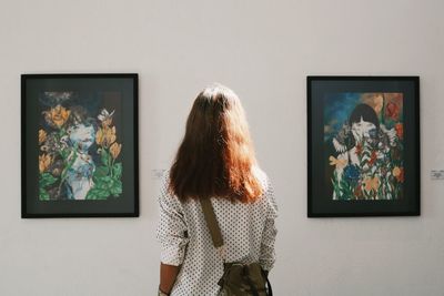 Rear view of woman standing against wall in museum