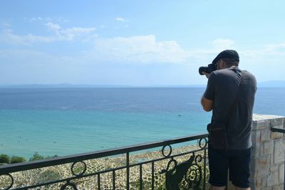 Rear view of woman photographing sea against sky