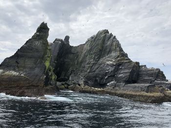 Scenic view of rocks by sea against sky