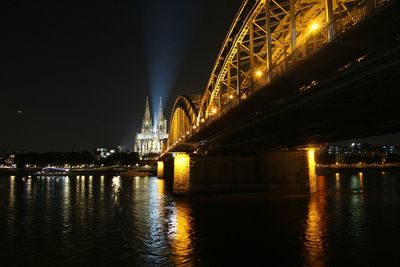 Illuminated hohenzollern bridge over rhine river against cologne cathedral