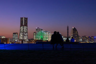 Illuminated modern buildings in city against sky at night