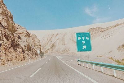 Information sign on road against sky