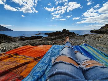 Low section of people on beach against sky