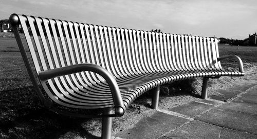 Empty bench with chairs in background