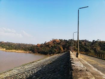 Road by lake against blue sky