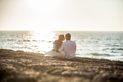 Rear view of couple sitting on beach