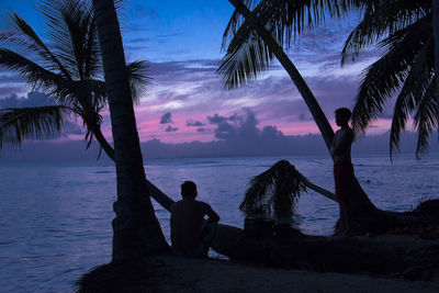 Silhouette men on beach against sky at sunset