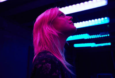 Pink light falling on smiling young woman in illuminated room