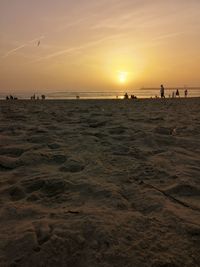 Silhouette people on beach against sky during sunset