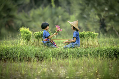 Rear view of people on grass in field