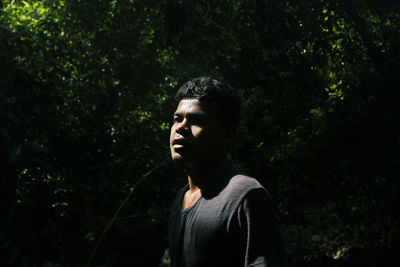 Portrait of young man looking away in forest