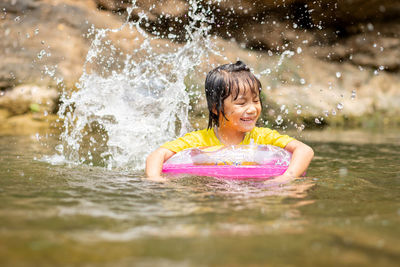 Smiling girl with inflatable ring swimming in lake