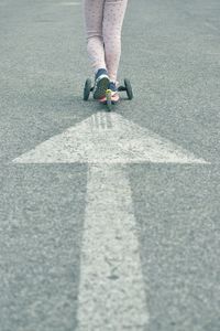 Low section of woman skateboarding on road