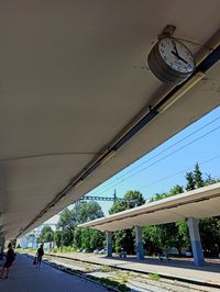 People walking on bridge by building against sky