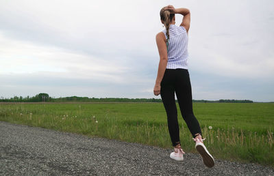 Rear view of man standing on field against sky