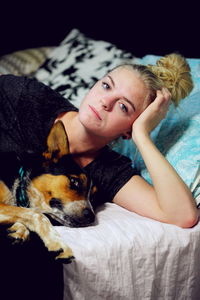 Portrait of woman with pembroke welsh corgi on bed