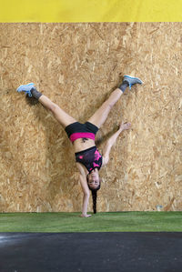 Fit woman doing handstand in the gym.