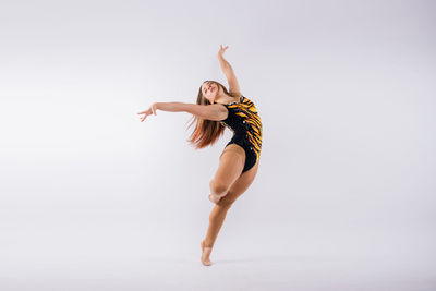 Portrait of young woman jumping against white background