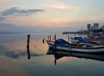 Boats moored in sea against sky during sunset