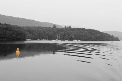 Yellow buoy in lake against sky