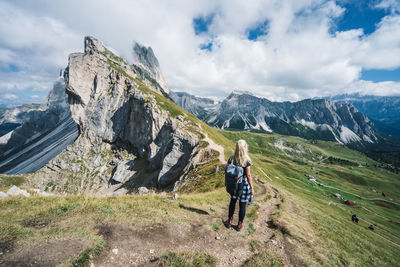 Rear view of man standing on mountain against sky