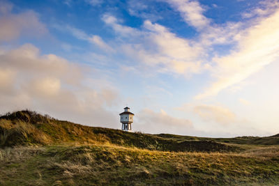 Lighthouse on street amidst buildings against sky