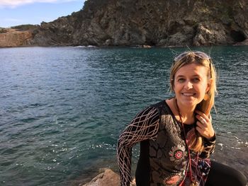 Portrait of smiling woman siting at sea shore