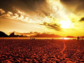 Scenic view of beach against cloudy sky during sunset