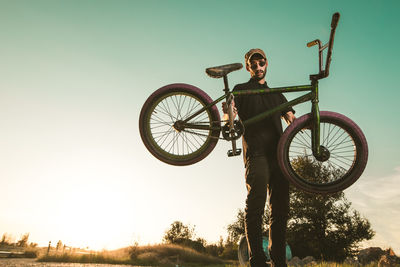 Man with bicycle against clear sky