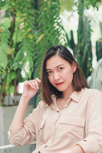 Portrait of young woman standing against plants