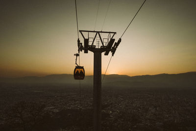 Low angle view of cableway against sky during sunset