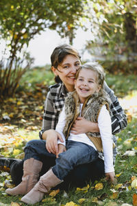 Portrait of happy mother and daughter sitting outdoors