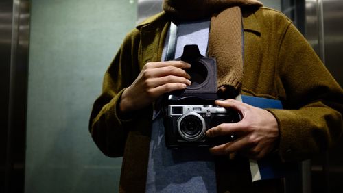 Midsection of man holding camera