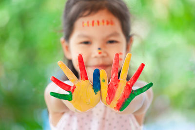 Close-up portrait of smiling girl showing colorful body paint on hands