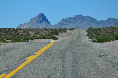 Surface level of road by mountains against sky