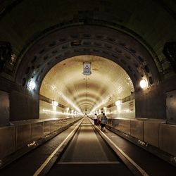 Rear view of people walking in illuminated elbe tunnel