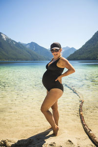 Portrait of pregnant woman rocking baby belly at the beach.