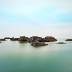 Scenic view of rocks in sea against sky