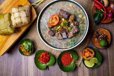 Coto makasar and ketupat, indonesian traditional food, taken with high angle view on table
