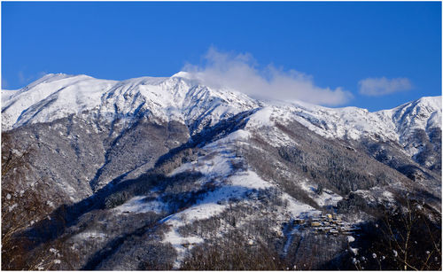 Scenic view of snowcapped mountains against blue sky