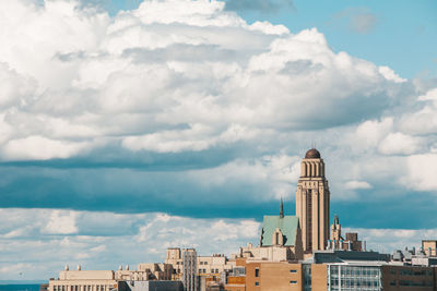 Buildings in city against cloudy sky