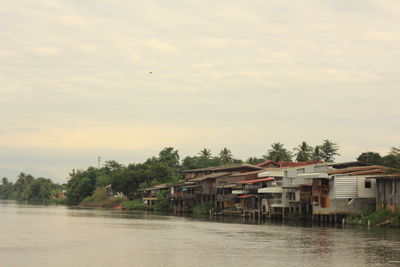 Houses by river against sky during sunset