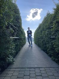 Rear view of man standing on footpath amidst trees