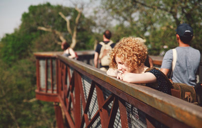 Smiling young woman standing by railing at park