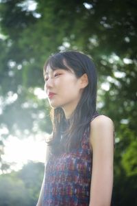 Beautiful young woman standing against tree